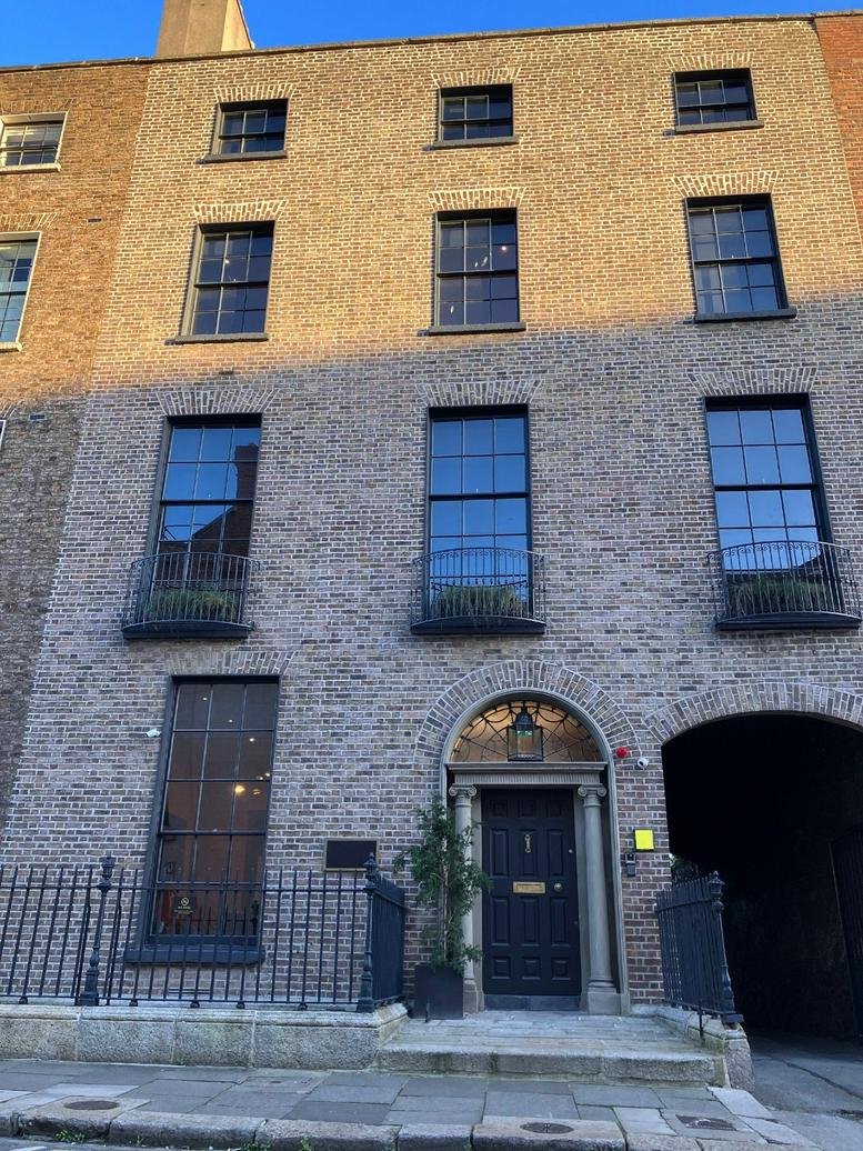 Exterior brick facade of Ten Ely Place, Dublin, Ireland, with a black arched door.