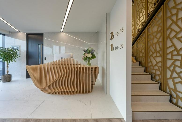 Reception area of The Embassy featuring a unique wave-patterned wooden desk and staircase.