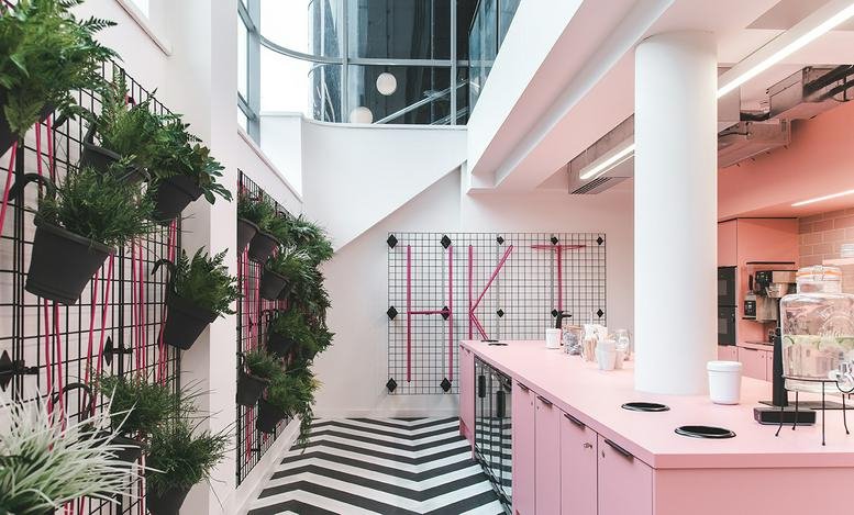 Spacious communal lounge at The Express Building, 9 Great Ancoats Street with pink accents and hanging plants.