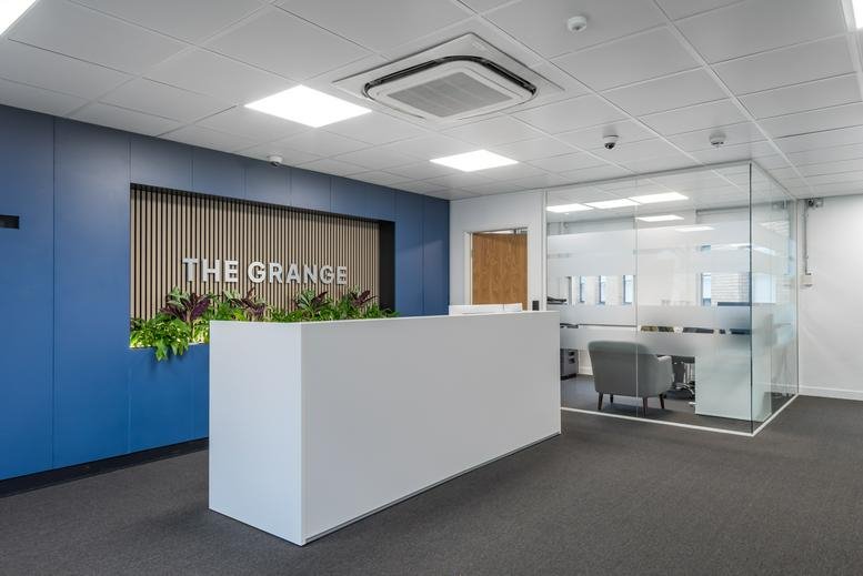 Bright reception desk with blue feature wall and signage for The Grange.