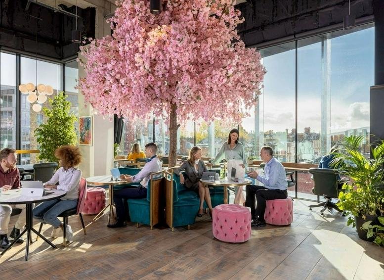 Spacious communal lounge at The Lennox Building featuring a large pink cherry blossom tree and velvet seating.