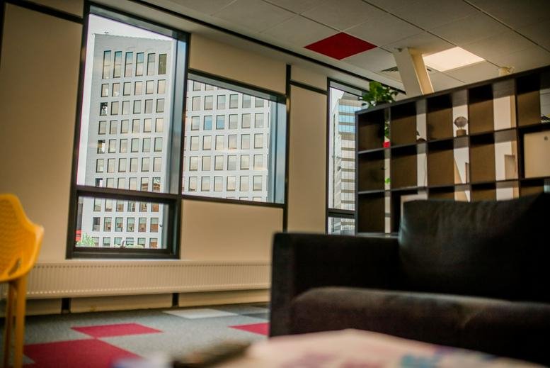 Lounge area at The Office, BCR Building with a dark sofa and city views through large windows.