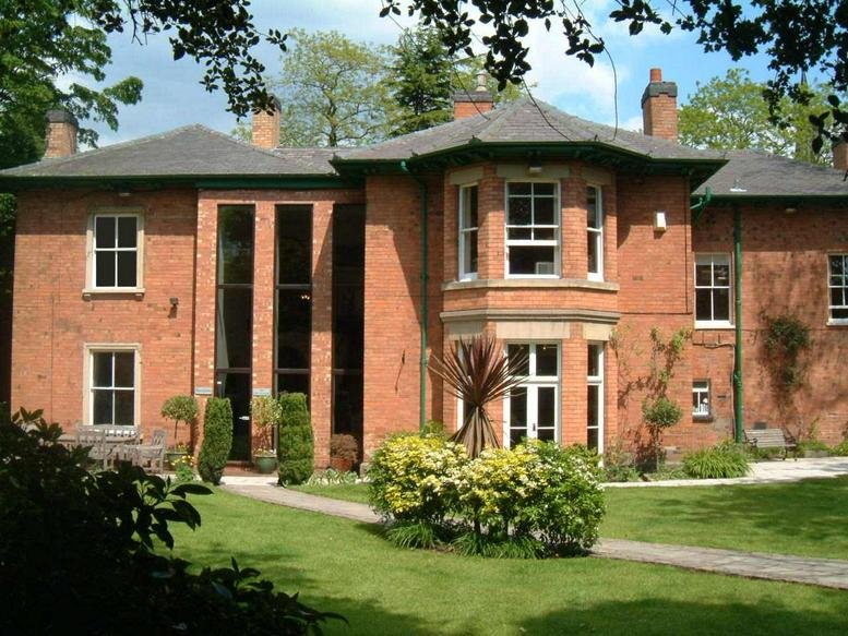 Exterior view of the red brick facade and gardens at The Old Vicarage.