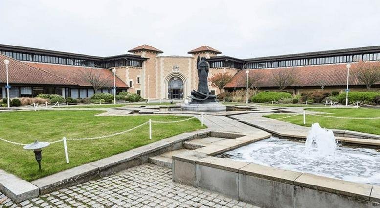 Exterior view of the grand stone entrance and courtyard at The Pearl Centre.