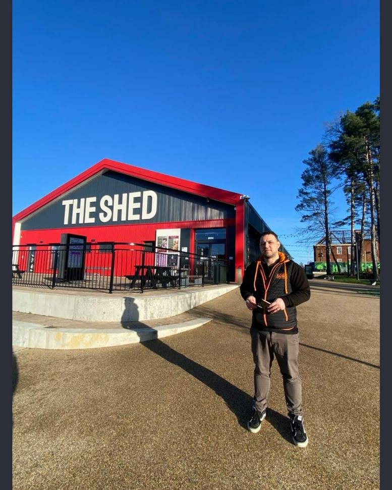 Exterior view of the red and grey building at The SHED, SERGEANTS YARD on a sunny day.