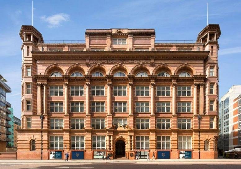 Grand brick exterior of The Tootal Buildings, Broadhurst House, featuring ornate arches and twin corner towers.