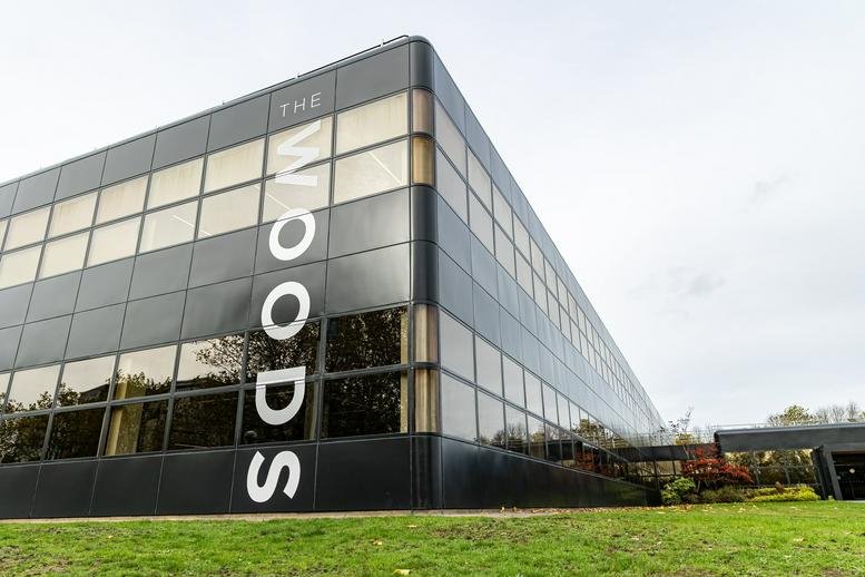 Exterior of the glass-facade building The Woods with large vertical signage.