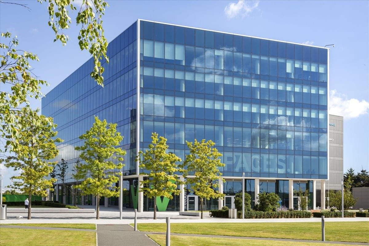 Exterior view of the glass-facade Two Dublin Airport Central building surrounded by greenery.