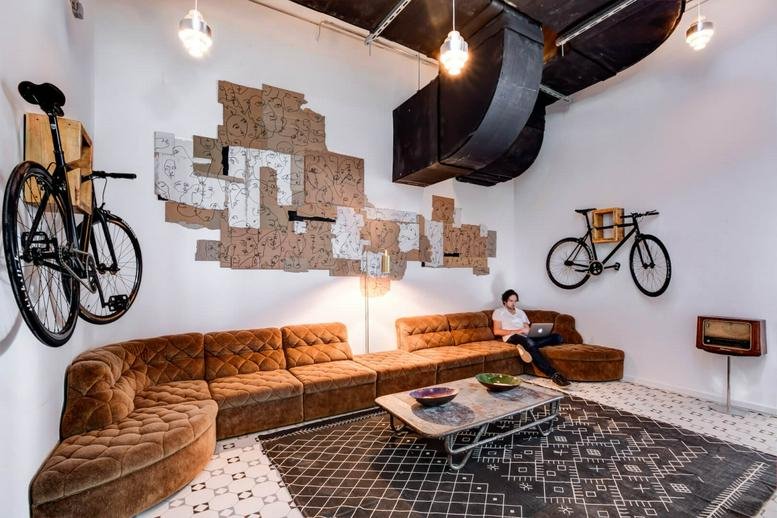 Spacious communal lounge at Uhlandstraße 32, Berlin, Brandenburg featuring a velvet sofa and bicycle wall mounts.