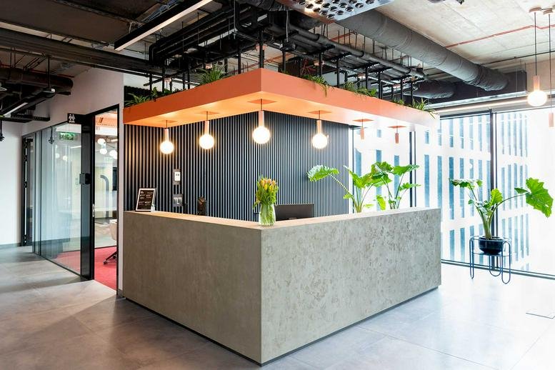 Modern reception area at Ul. Żelazna 2 with a stone desk, hanging globe lights, and indoor plants.