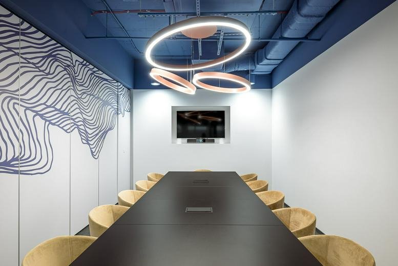 Perspective view of a long black conference table with plush tan seating.