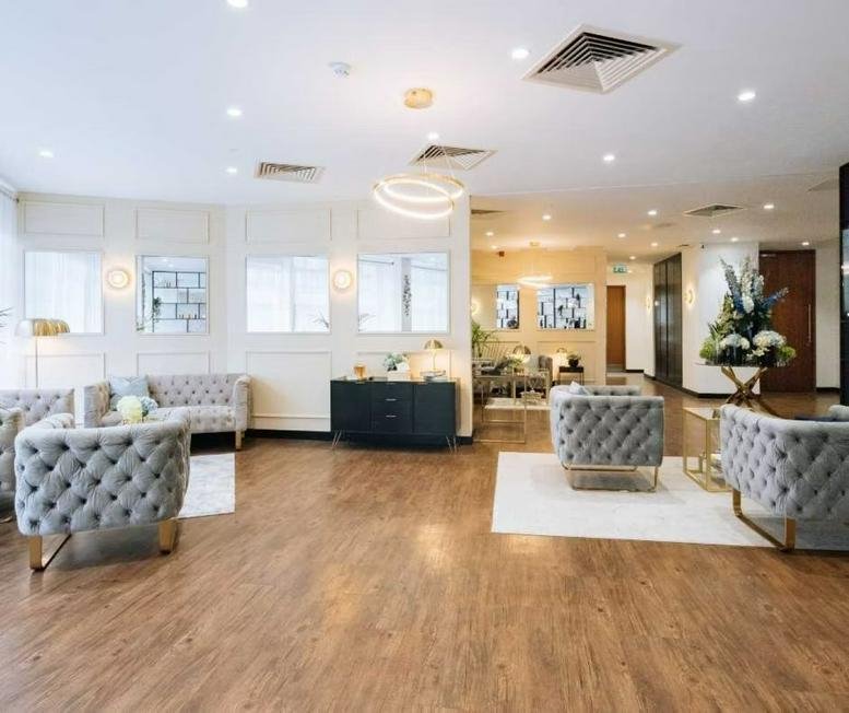 Spacious reception lounge at Upper Berkeley Street, Mayfair, London featuring tufted grey velvet armchairs.