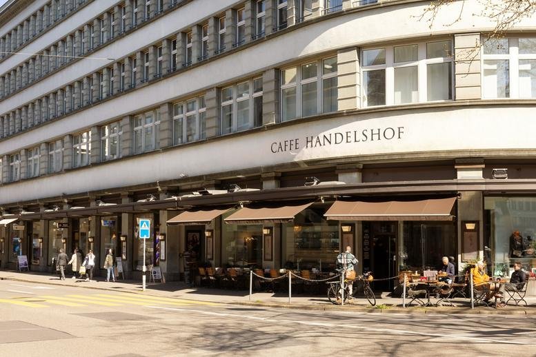 Exterior view of the Handelshof building featuring street-level cafes and classic architecture.