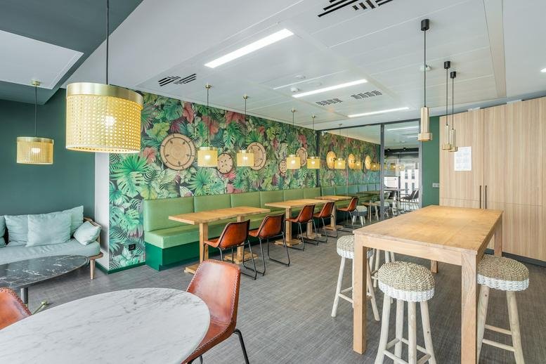 Spacious communal dining area with jungle-themed wallpaper and woven pendant lights at Utopicus Diagonal.