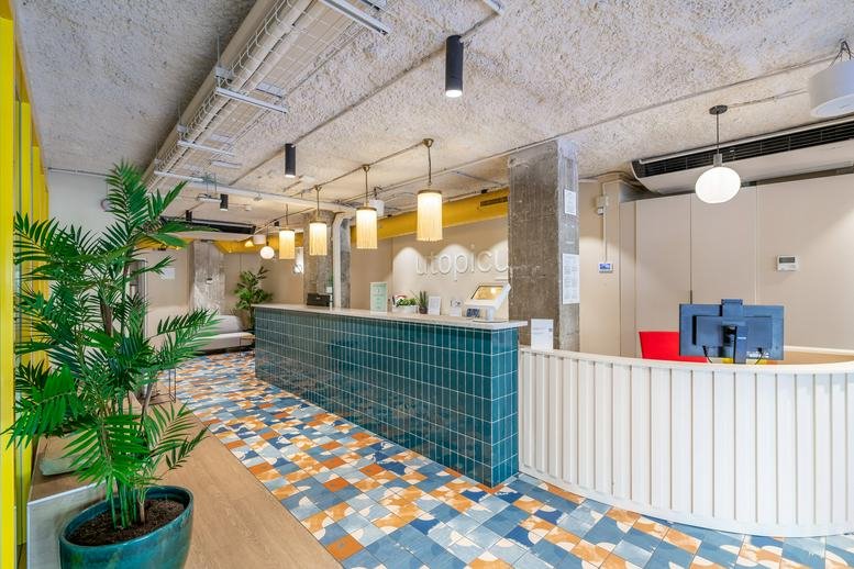 Reception area of Utopicus Gal·la Placidia with a blue tiled desk, patterned floor, and vibrant plants.