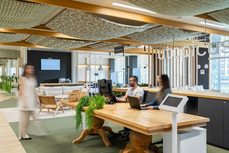 Spacious communal lounge at Utopicus Glòries with wood tables and decorative fabric ceiling panels.
