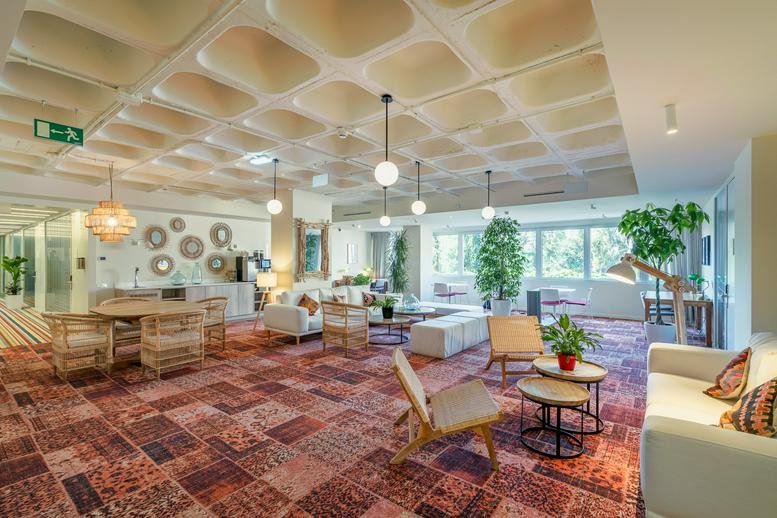 Spacious communal lounge at Utopicus José Abascal featuring a unique coffered ceiling and eclectic patterned carpet.