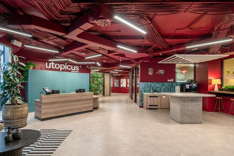 Spacious reception area with a wooden desk and bold red ceiling at Utopicus Príncipe de Vergara.