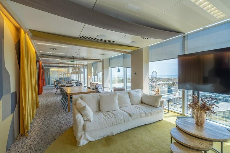Spacious lounge at Utopicus Torre Marenostrum with a large white sofa, yellow rug, and floor-to-ceiling windows.