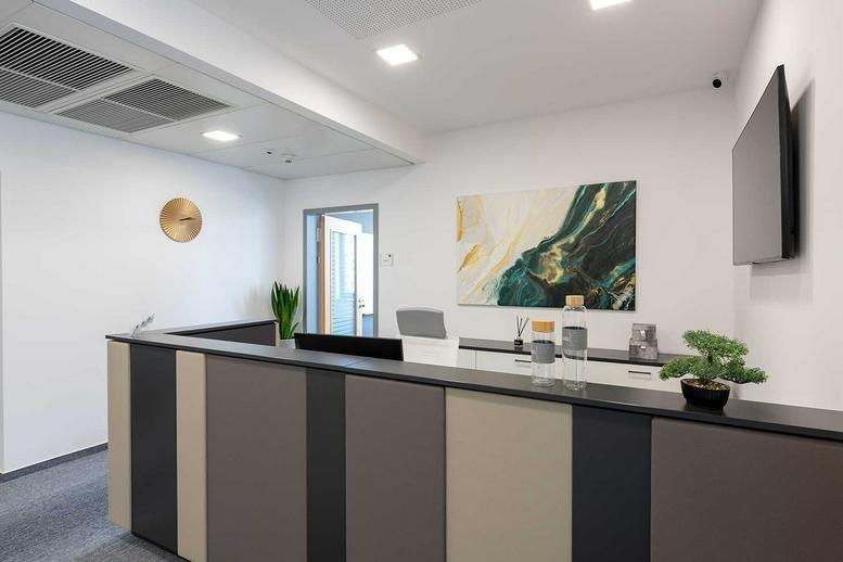 Modern wood-paneled reception desk at Váci út 76, Budapest with abstract art and a flat-screen TV.