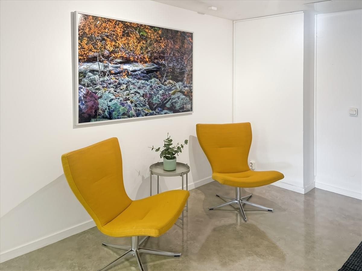 Reception area at Västra Tullgatan 6, Hudiksvall with yellow armchairs and a nature painting.
