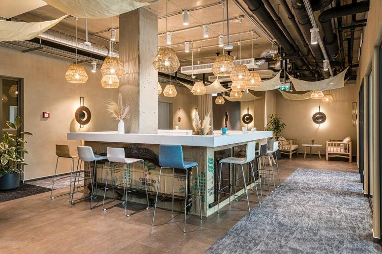 Spacious communal lounge at H2Offices Business Centre, 23-27 Vaci Utca, Budapest with a bar and woven pendant lights.