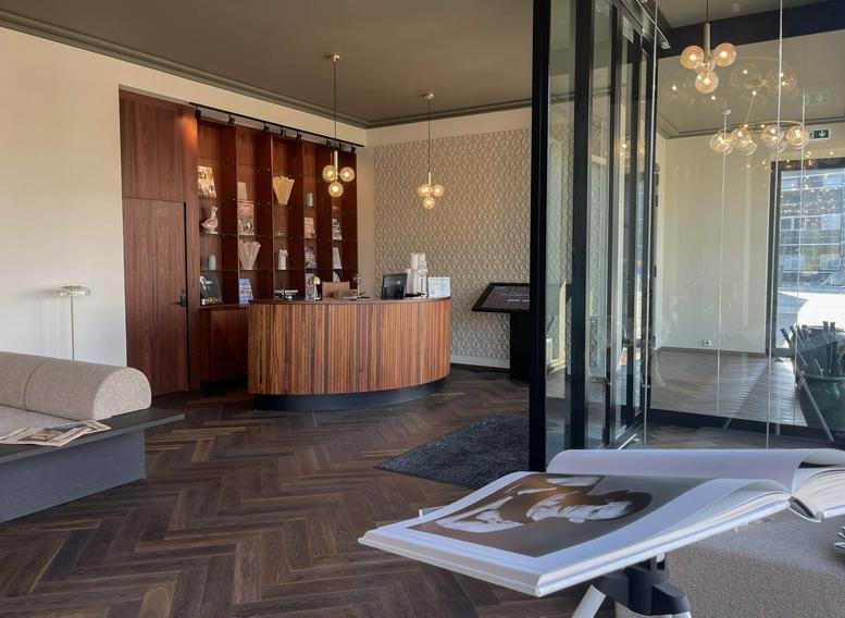 Spacious reception area at Vandtårndsvej 77, Søborg, Copenhagen with a curved wooden desk and parquet floors.