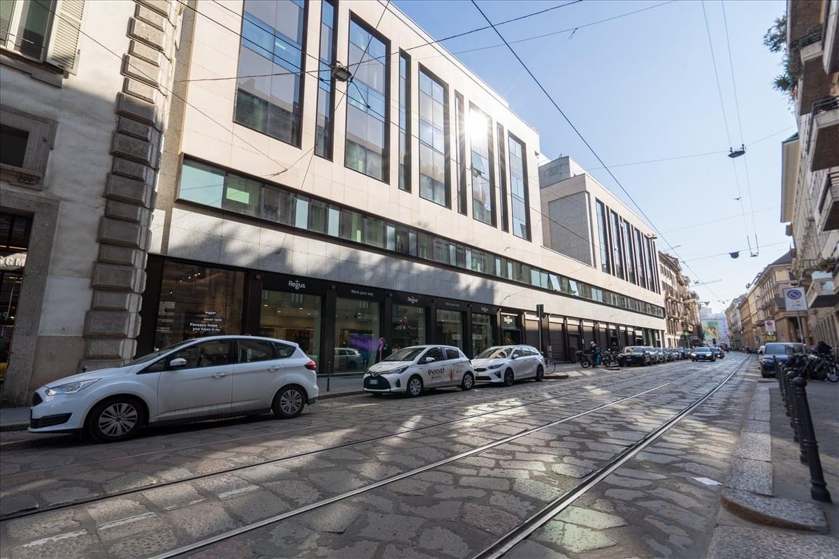 Exterior view of the stone and glass facade building at Via Broletto 46, Milan, Italy.