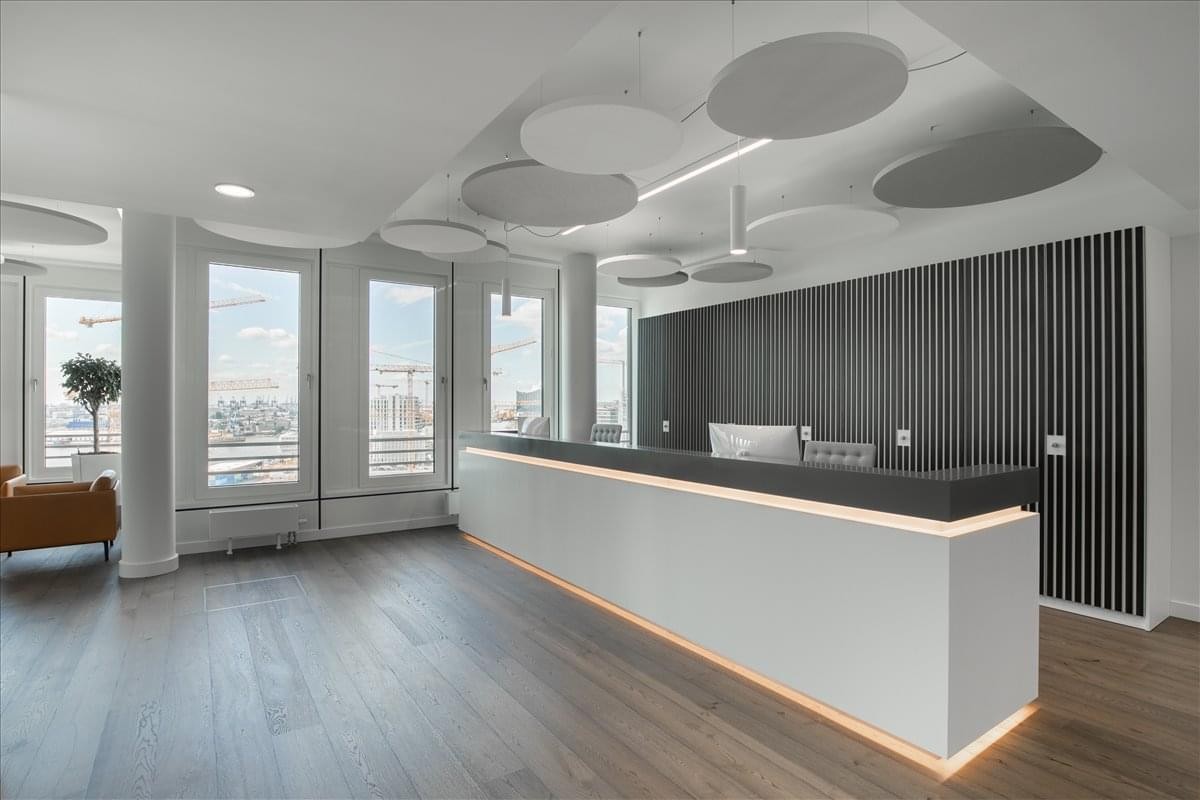Bright reception desk with warm under-lighting and decorative circular ceiling panels at Via Dei Pontefici 3, Rome.