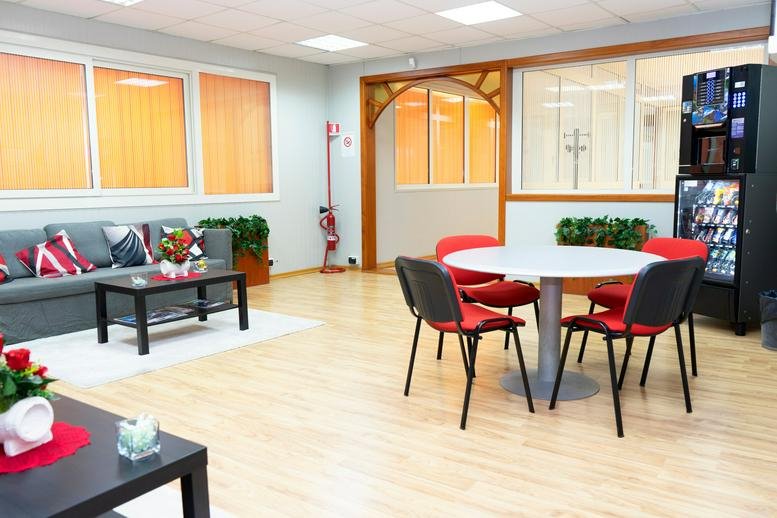 Spacious communal lounge at Via Eleonora Duse, 26/b with sofa, coffee table, and vending machines.