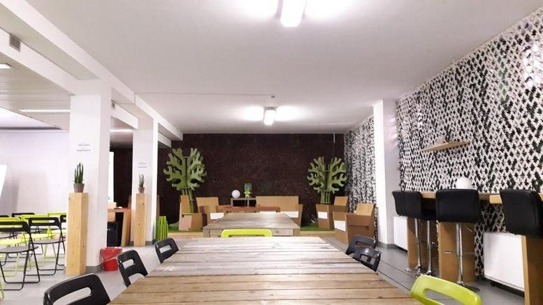 Spacious communal lounge at Via Merano 16 with wooden tables, patterned wallpaper, and tree-like floor lamps.