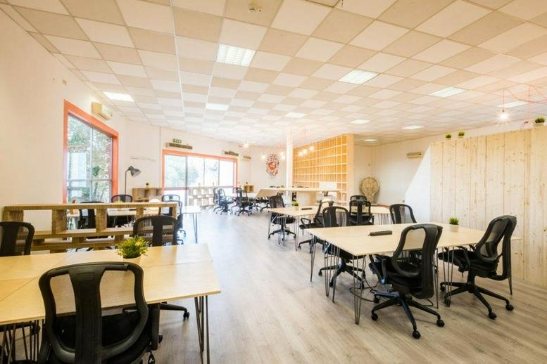 Spacious open-plan workspace at Via Quinto Publicio, 90 with wood-topped desks and ergonomic black chairs.