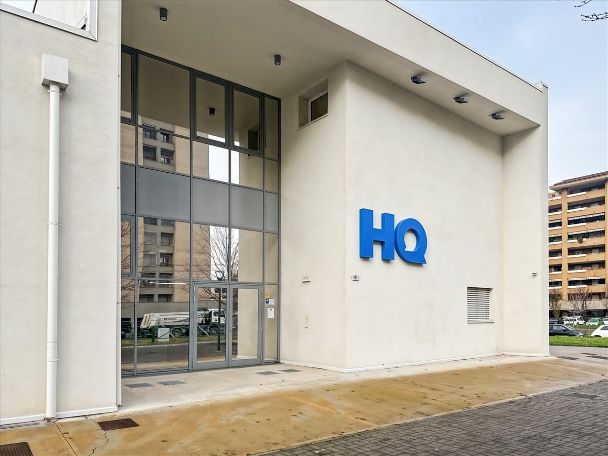 Exterior view of the modern white HQ building at Via Roberto Tremelloni 31.