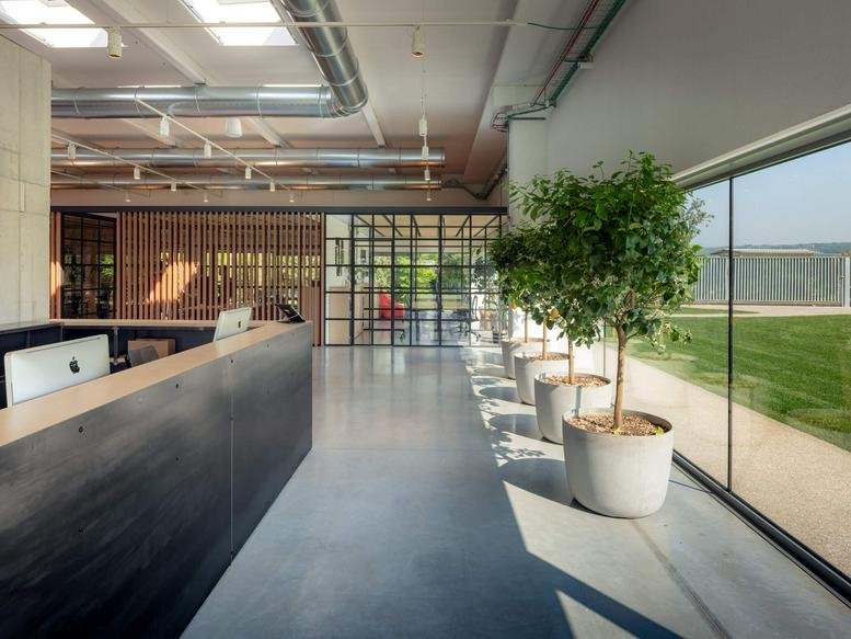 Spacious reception area at via San Gaetano 113/A, Montebelluna, Treviso with a sleek dark desk and potted trees.