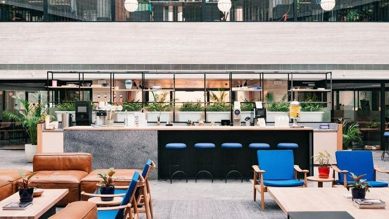 Spacious communal lounge and cafe at Via Vittor Pisani, 15, Milan with a marble bar and blue stools.