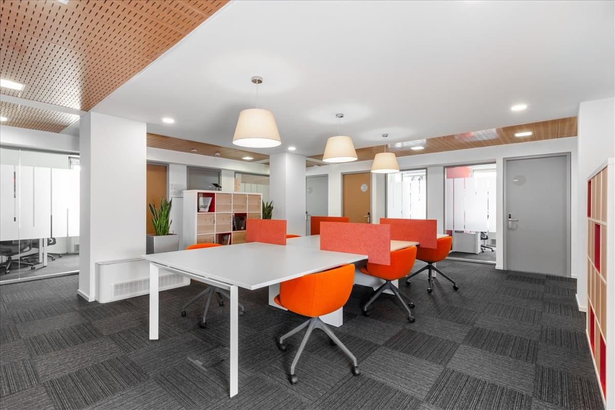 Bright open-plan workspace at Via XII Ottobre 1, 6th floor, Genova with orange chairs and modern pendant lighting.