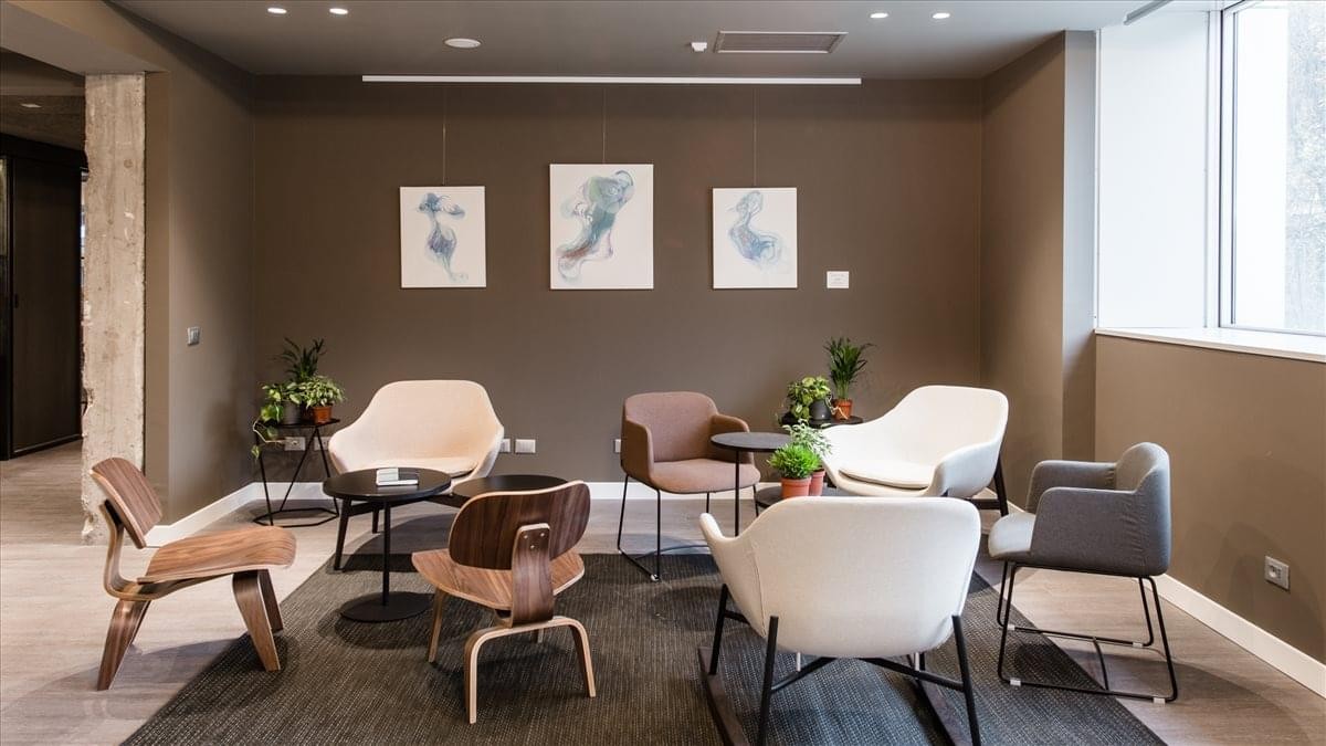 Spacious reception lounge at Via Zuretti 34 with designer armchairs and abstract wall art.