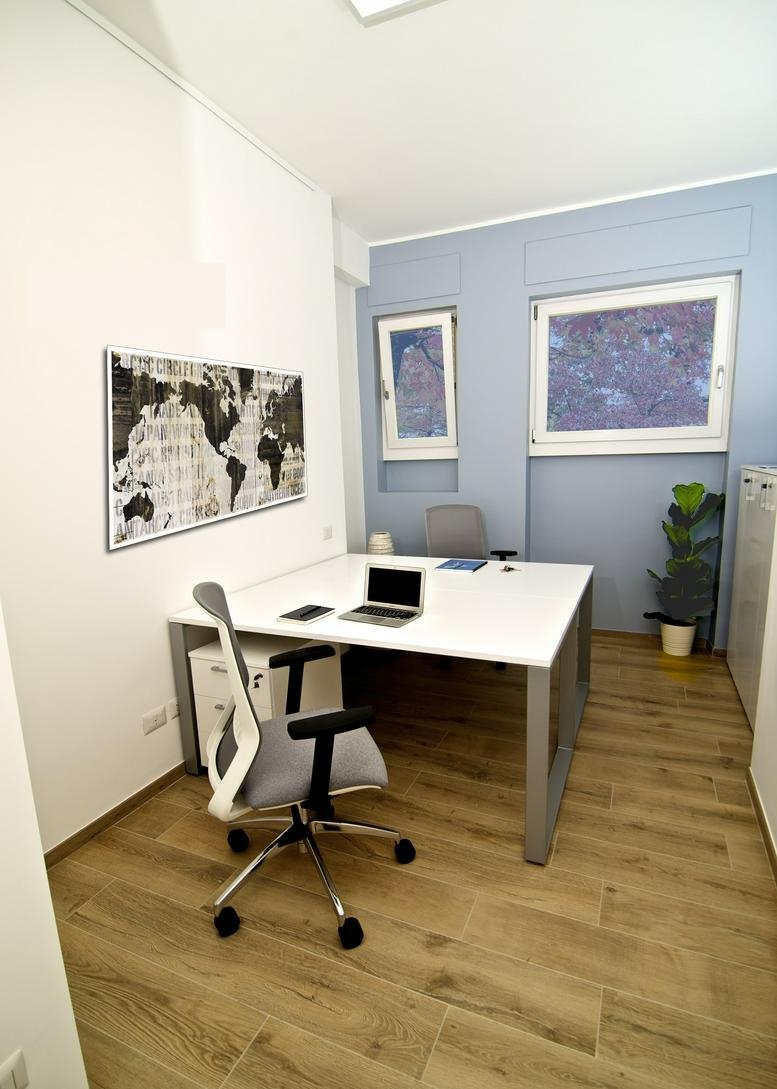 Modern office interior at Viale Europa 55, Rome, Italy featuring a white desk, ergonomic chair, and world map art.