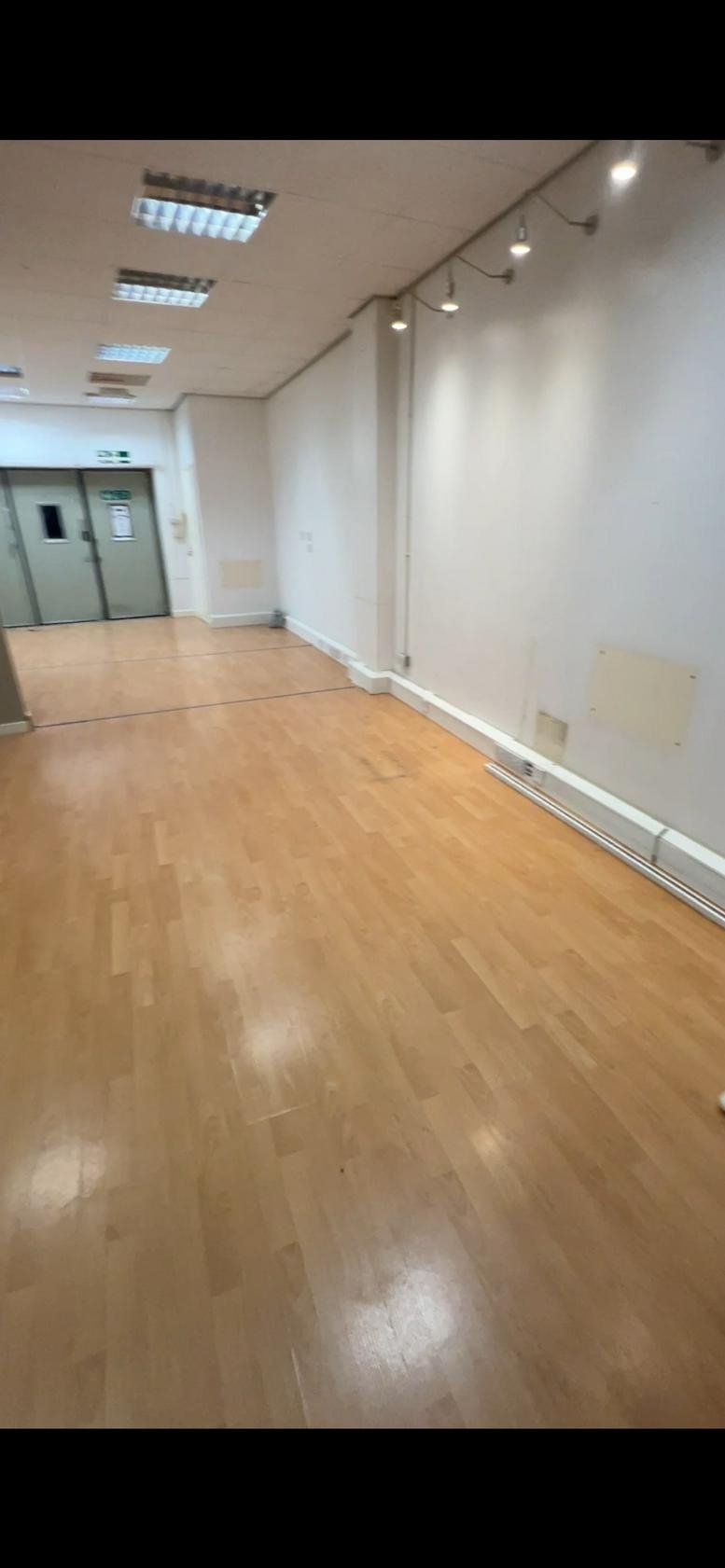 Spacious interior at victoria place, London, United Kingdom with light wood flooring and overhead spotlighting.