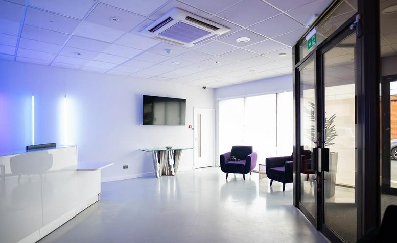 Bright white reception area at Victory House, Chobham Street, Luton, featuring a sleek desk and blue lighting.