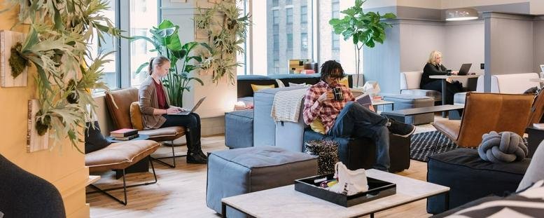 Spacious communal lounge at Warschauer Platz 11-13 featuring comfortable seating and lush indoor plants.