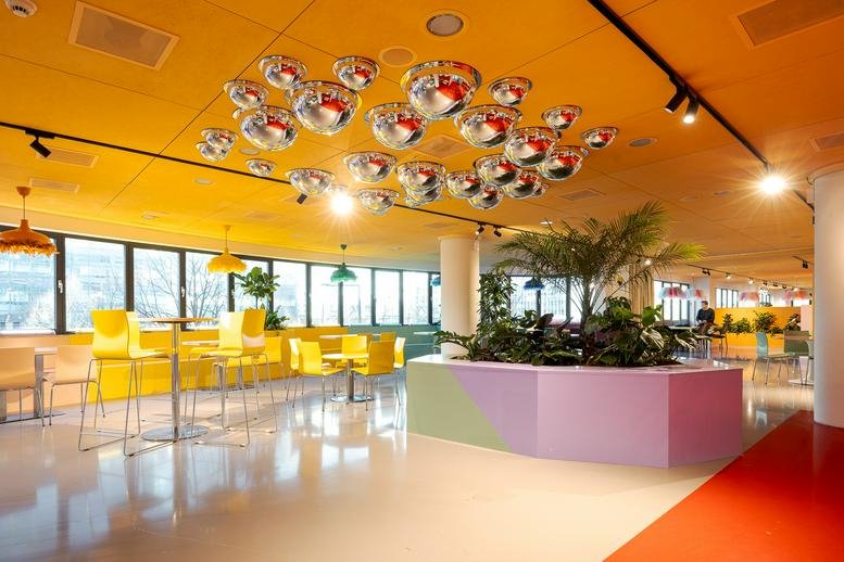 Spacious breakout area featuring unique overhead mirror art and lush indoor plants.