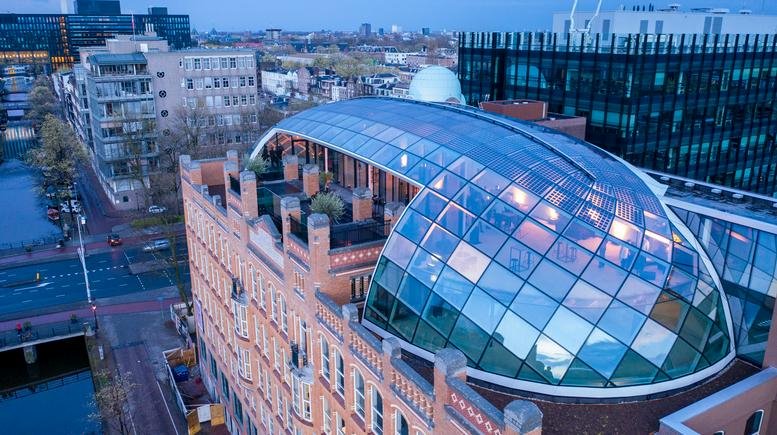 Exterior of the historic brick building at Weesperplein, 4a featuring a modern glass dome roof extension.