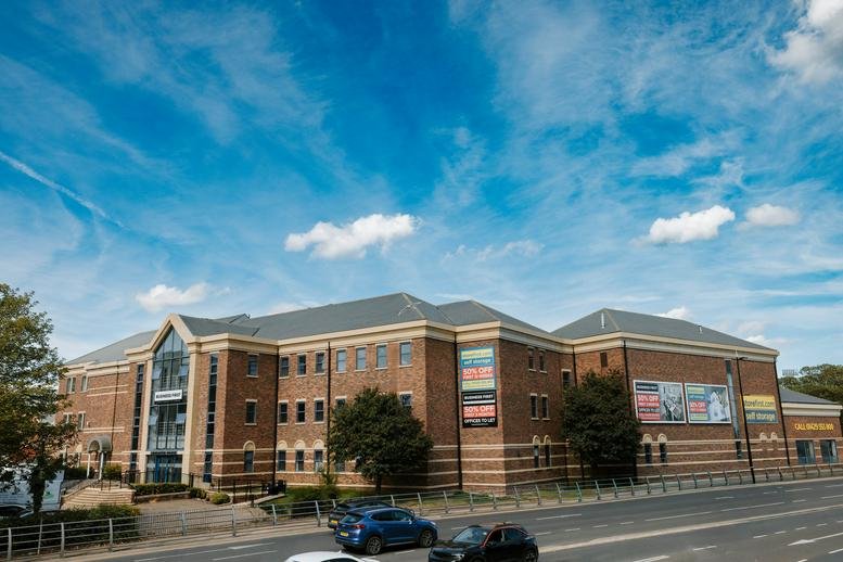 Wide view of the brick office building exterior under a bright blue sky.