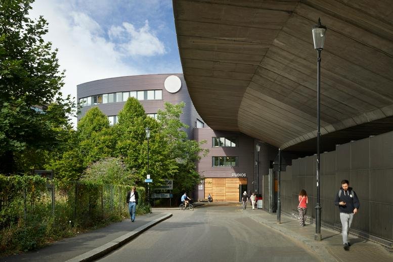 Exterior entrance of Westbourne Studios featuring a modern curved building under a concrete overpass.