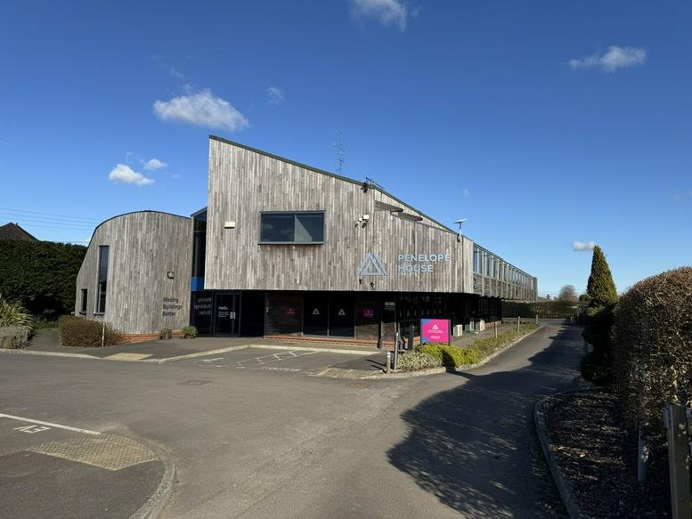 Exterior view of the wooden-clad Penelope House building under a bright blue sky.