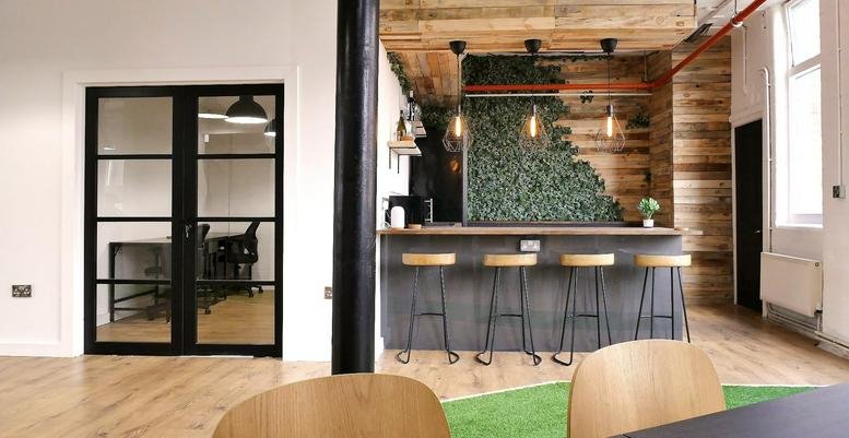 Spacious breakout area at Western House featuring a stylish bar, stools, and a green plant wall.