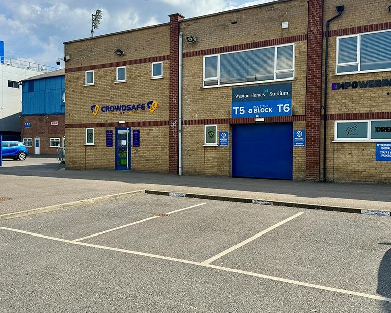 Exterior view of the brick facade at Weston Homes Stadium including the main entrance and blue doors.
