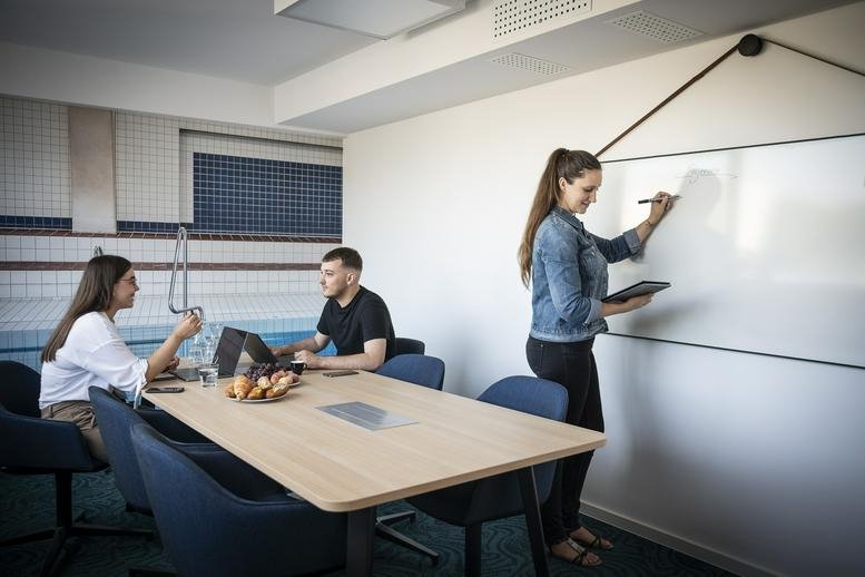 Bright conference room with a woman writing on a large whiteboard.