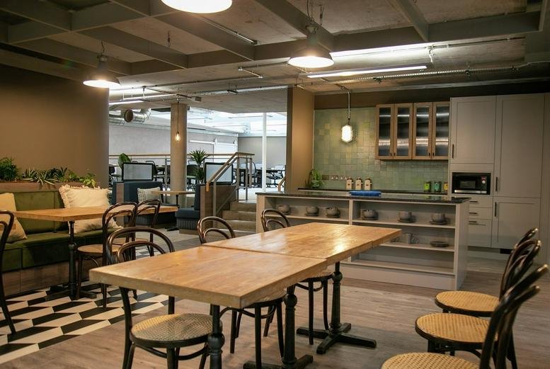 Spacious communal kitchen and dining area with wooden tables and industrial lighting at Woolyard.